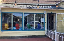 Yellow Store Front with UFO stickers on the windows. There is a walkway to the right that leads to the front door.