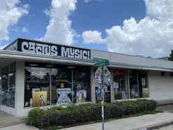 Outside view of a building. There is a sign that Cays "Cactus Music!" at the top, and there are several music artist posters in the windows.