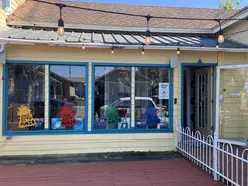 Yellow Store Front with UFO stickers on the windows. There is a walkway to the right that leads to the front door.