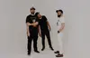 Members of Cope stand in front of a white background. Two wear all black, one wears all white. 