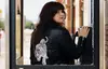 Roxanne is stood in an old, smashed payphone box. She is wearing a black, leather jacket with a white tiger on the back of it. The photograph is taken from behind, with Roxanne looking over her right shoulder to face the camera.